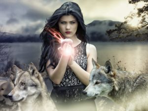 A light skinned young woman seen from the hips up with black hair and a lacy black sleeveless shirt. She's holding an apple, which is glowing. Two wolves stand by her, their heads at her waist. Behind her, a snowy wooded shoreline and a lake with hills on the other side of the lake.