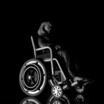 Black background with a grayscale woman in a wheelchair