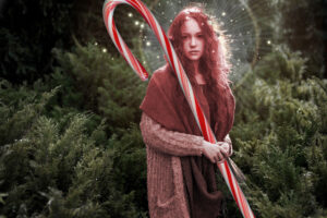 A pink tinted elf in a coniferous forest holding a giant candy cane